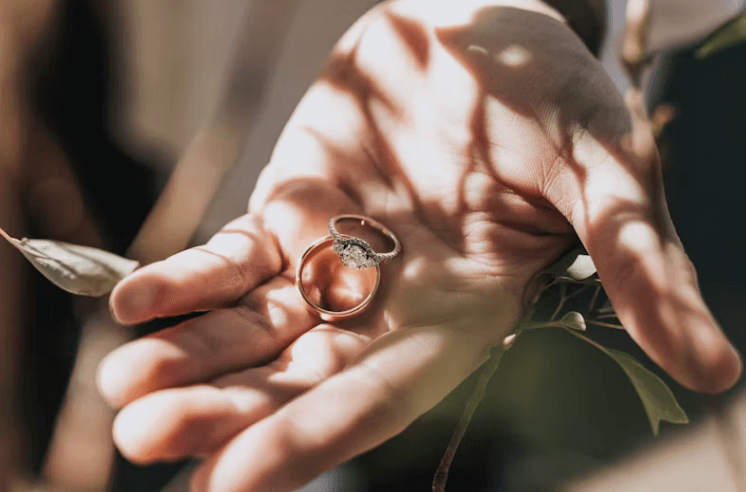 Engagement ring and wedding band in hand, highlighting care tips from Montreal jewelers Maison Karat on ring maintenance and 4Cs.