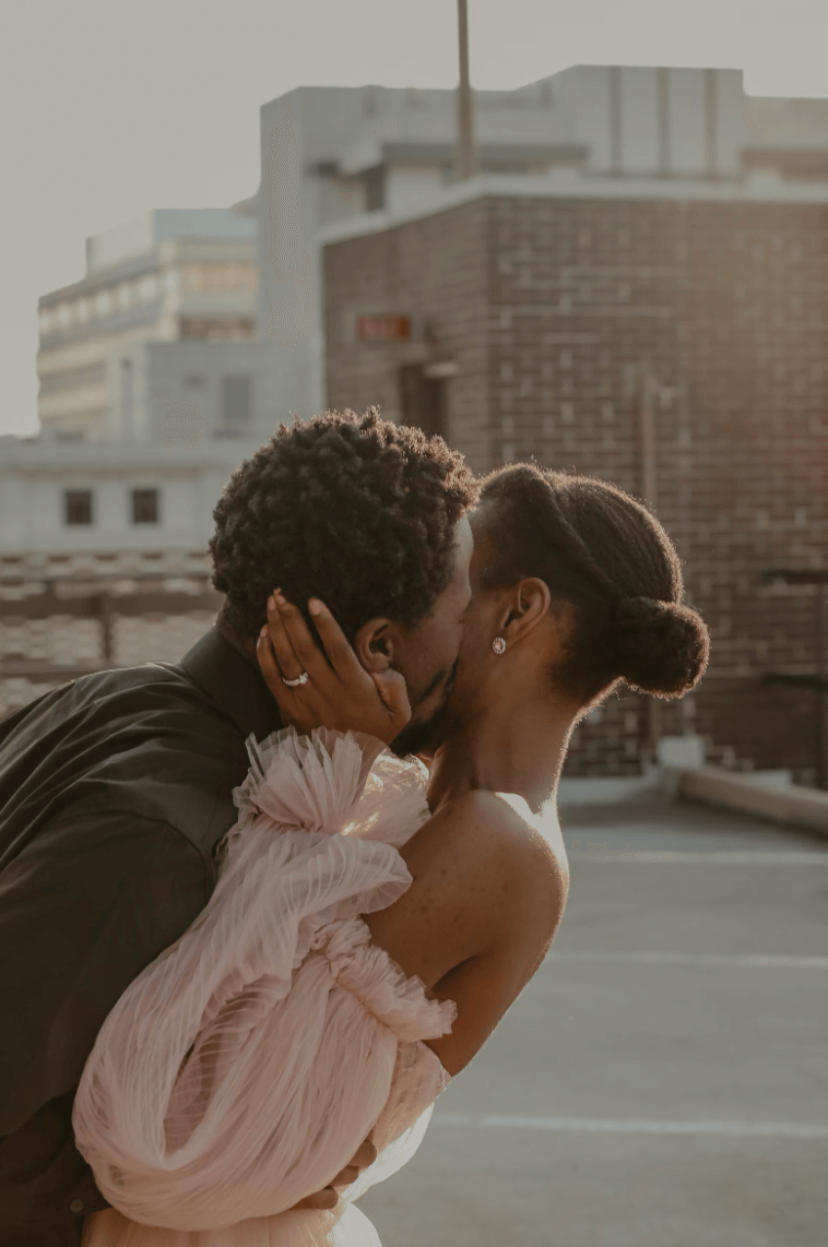 Couple kissing on rooftop, engagement ring visible, symbolizing love and commitment with eco-friendly rings in Montreal.