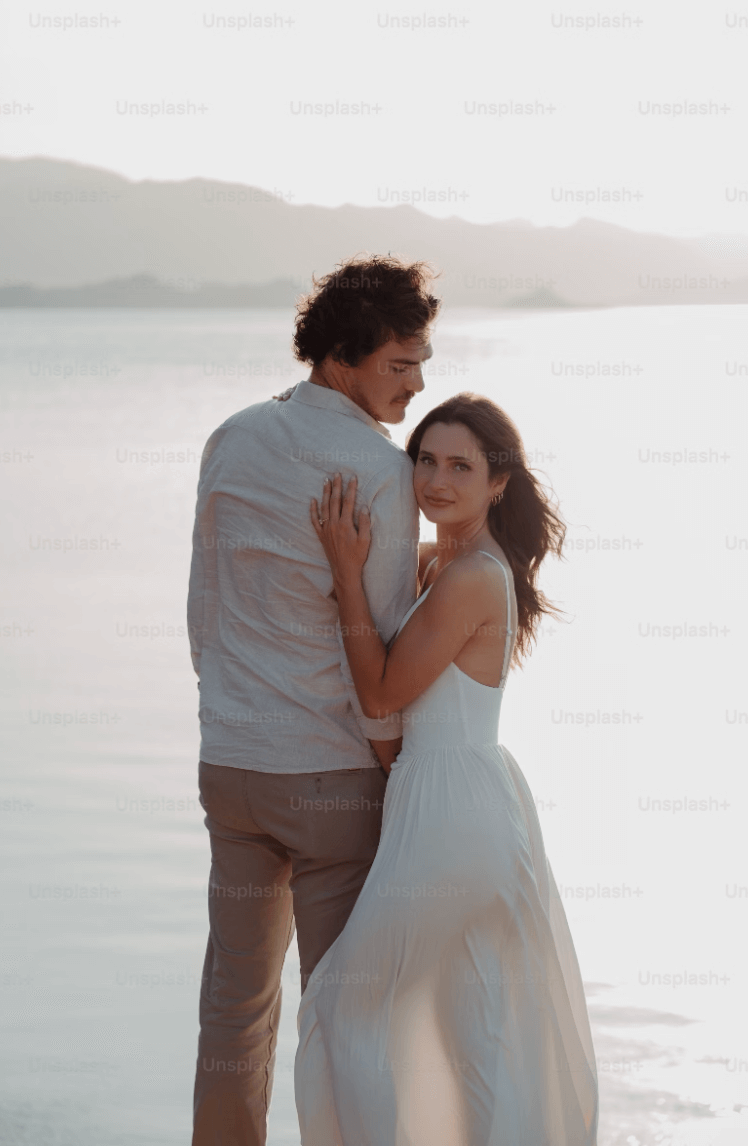 Romantic couple embracing by the beach at sunset.