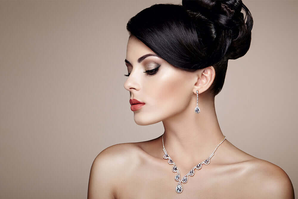 Elegant woman wearing custom jewelry set from Maison Karat, featuring intricate necklace and earrings highlighting personal style.